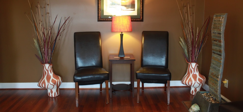 The reception lounge at Synergy, with two leather chairs, a lamp and a water feature