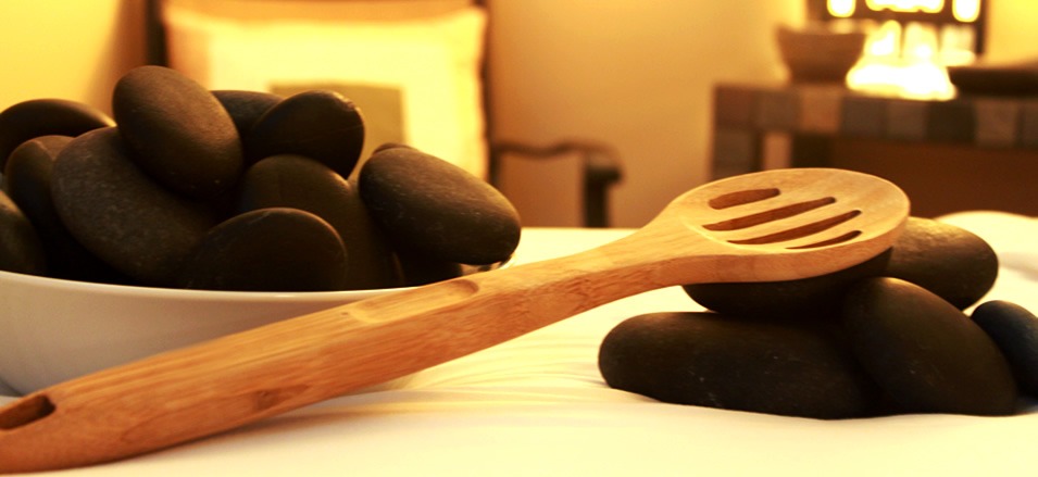 Heated basalt stones in a bowl beside a treatment table